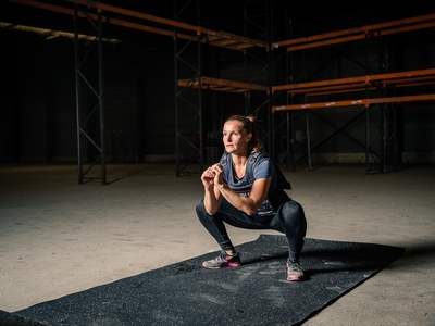 Femme en train de faire un squat sur un tapis de sol LEVEL addict